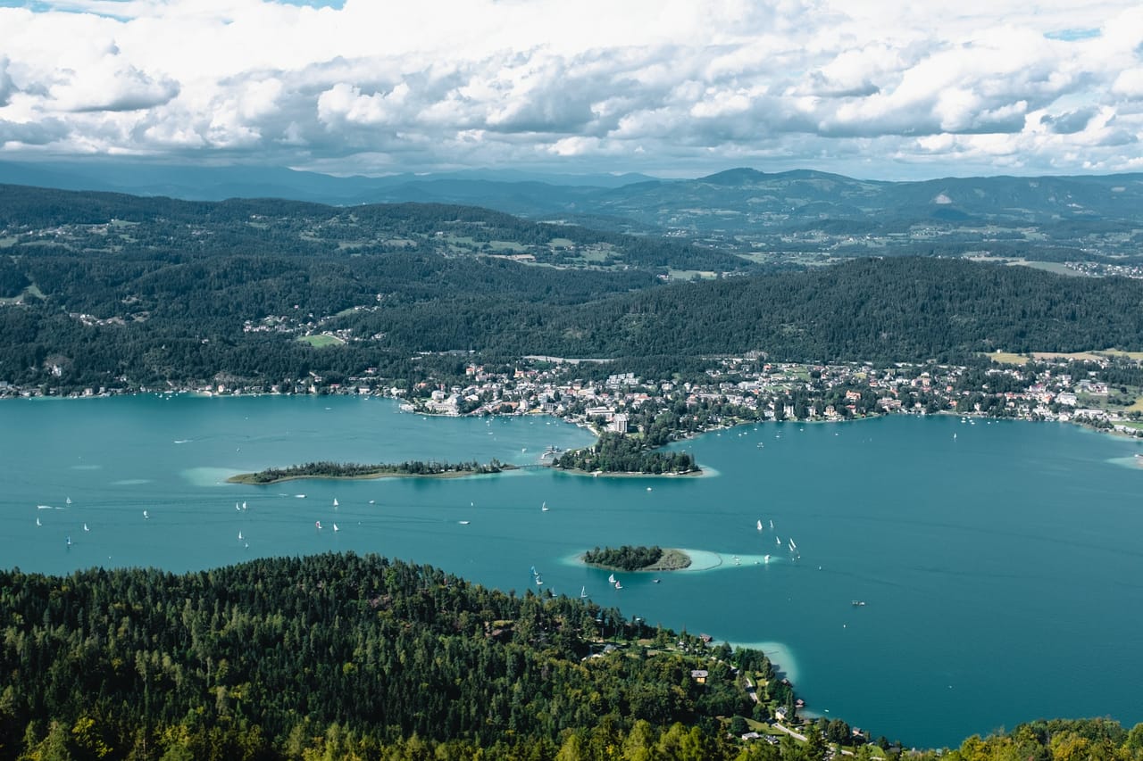 Blick über den türkisen Wörthersee auf die Ufer und Hügel bei Klagenfurt.